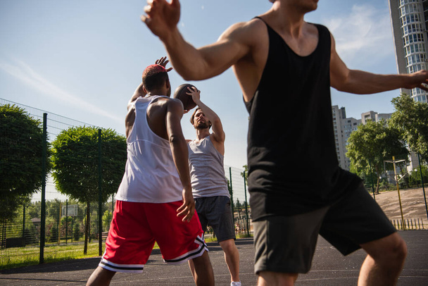 Multiethnic sportsmen playing basketball on playground  - Foto, Imagem