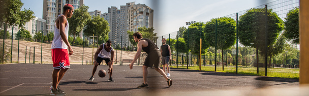 Jonge multi-etnische sporters basketbal spelen in de buurt van vrienden buiten, banner  - Foto, afbeelding