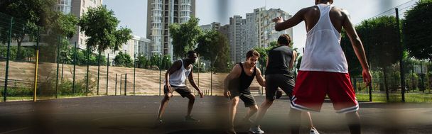 Sportsman playing streetball with multiethnic people on outdoor playground, banner  - 写真・画像