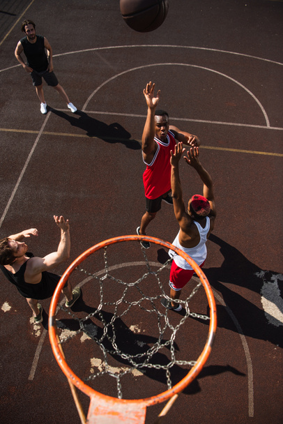 Overhead view of interracial men playing basketball near hoop  - Foto, imagen