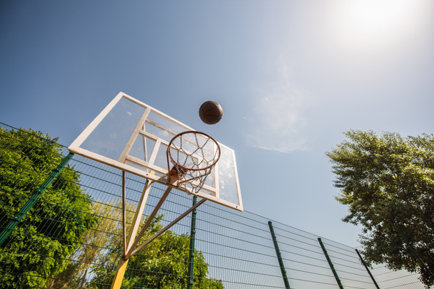 Low angle view of basketball ball near hoop on playground outdoors  - Фото, зображення