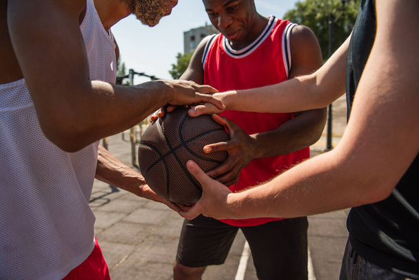 Multiethnic sportsmen holding basketball ball outdoors  - Foto, Imagem