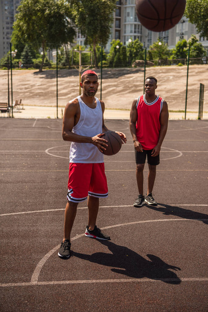 African american sportsmen looking at basketball ball on playground  - Fotografie, Obrázek