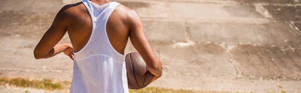 Vista recortada del hombre afroamericano sosteniendo pelota de baloncesto al aire libre, pancarta  - Foto, imagen