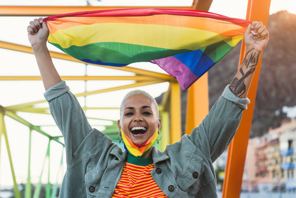 Giovane donna che celebra l'orgoglio gay con bandiera arcobaleno simbolo della comunità LGBTQ - Foto, immagini