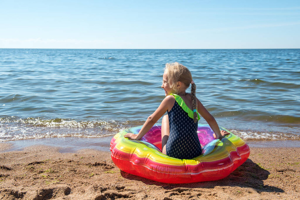 Retrato de niña con círculo de goma inflable en la playa - Foto, Imagen