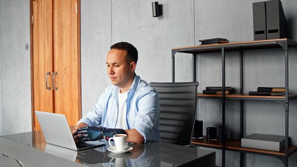 Концентрований чоловік хакер з чорними типами біологічних рук на сірому ноутбуці, сидячи за столом
 - Фото, зображення
