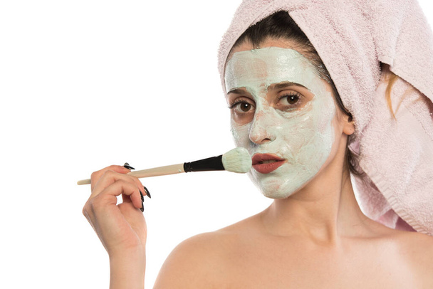 mladá žena s obličejovou maskou na obličeji použití kosmetické krém na hlavě - Fotografie, Obrázek