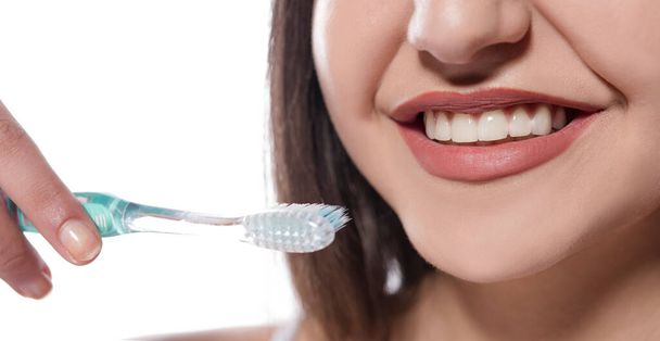 όμορφη νεαρή γυναίκα με οδοντόβουρτσα σε λευκό φόντο - Φωτογραφία, εικόνα