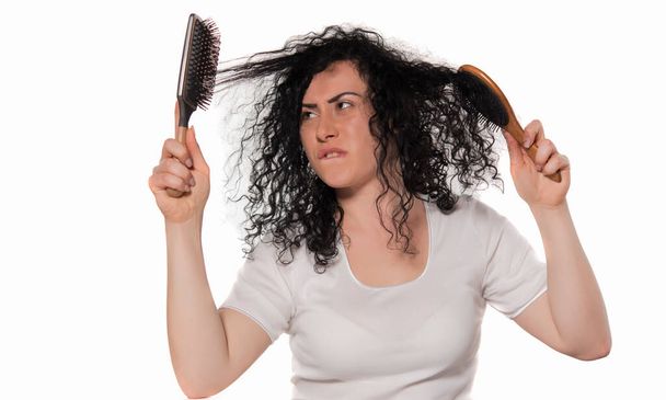 νεαρή γυναίκα με χτένα μαλλιά και βούρτσα μαλλιών που απομονώνονται σε λευκό - Φωτογραφία, εικόνα