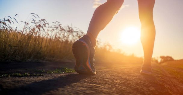 Pernas atleta corredor correndo em um close-up de uma trilha através de um campo. - Foto, Imagem