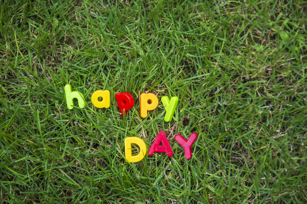 letras de día feliz escrito con letras de juguete en la hierba en el jardín de la casa - Foto, Imagen