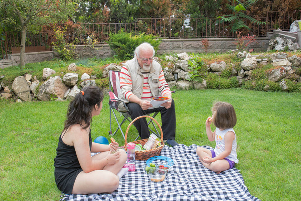 Les filles pique-niquent avec leurs grands-parents. Le vieil homme est assis sur la chaise. - Photo, image