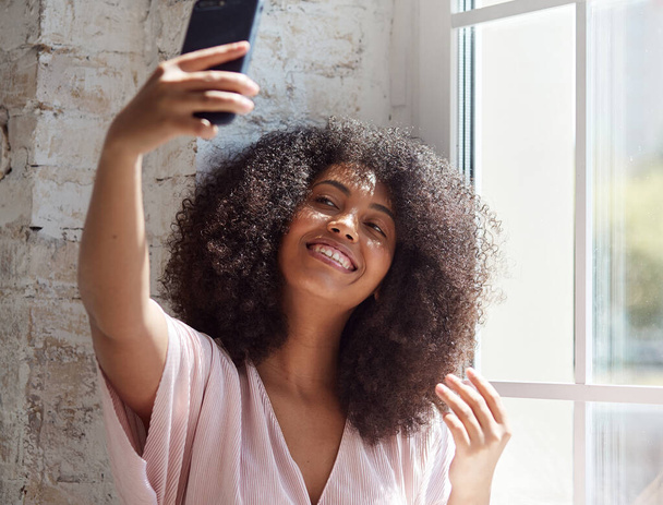 Jonge gemengde ras vrouw kijken naar smartphone scherm, het doen van selfies - Foto, afbeelding