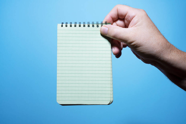 a notepad in a man's hand with the blue background - Fotó, kép