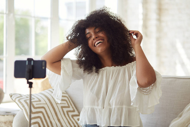 Kadın siyah vlogger etkileyicisi evde oturup kameraya bakıyor., - Fotoğraf, Görsel