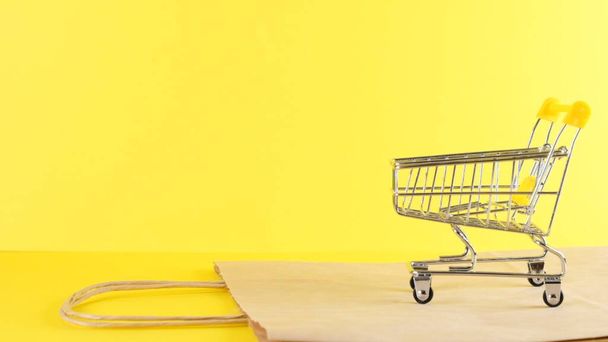 黄色の背景に空のショッピングカート、クローズアップ。ブラックフライデーショッピング&割引コンセプト - 写真・画像