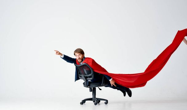 a man in a suit with a red cloak rides in a superman chair - Photo, Image
