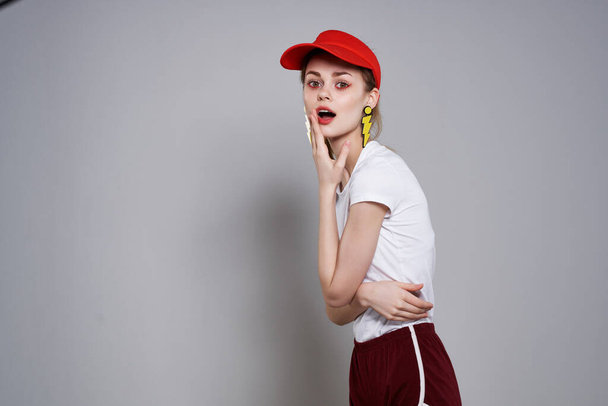 emocjonalna dziewczyna w czerwonej czapce jasny makijaż żółte kolczyki biżuteria akcesoria - Zdjęcie, obraz