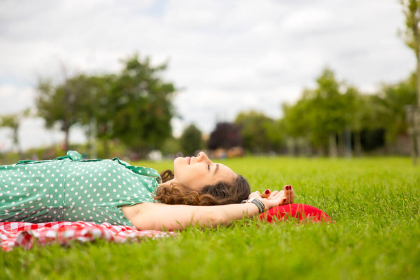 Young woman lying down on the grass and having a relaxing day - Zdjęcie, obraz