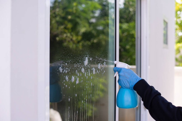 Hand in Hand und Reinigungsspray. Fenster und Türen zu Hause reinigen. - Foto, Bild