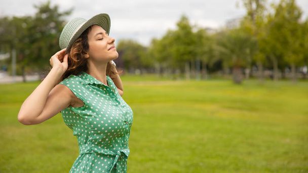 Young woman in straw hat is breathing fresh air in the park - Φωτογραφία, εικόνα