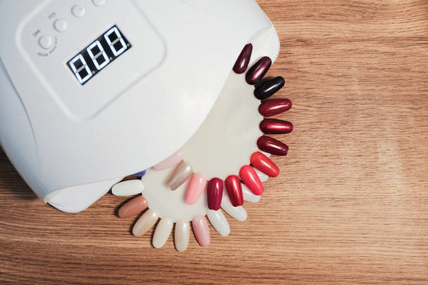 Des échantillons de vernis à ongles de différentes couleurs sont disposés sur la table de manucure pour montrer aux clients. - Photo, image