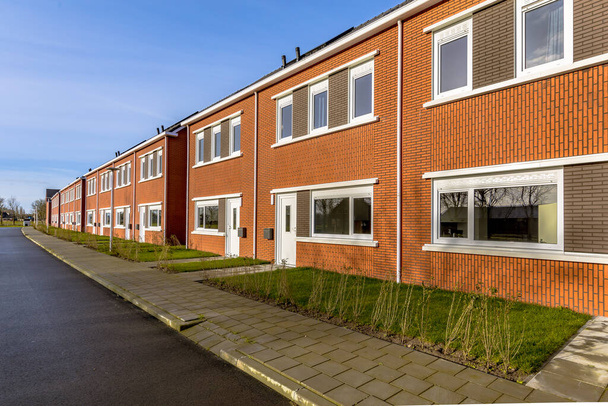 Nuevo desarrollo de viviendas públicas básicas en un pueblo de los Países Bajos. Barrio escena de calle con casas adosadas suburbanas modernas. - Foto, imagen