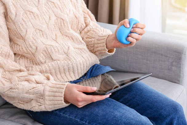 Nő szorító stressz labda használata közben tabletta számítógép - Fotó, kép