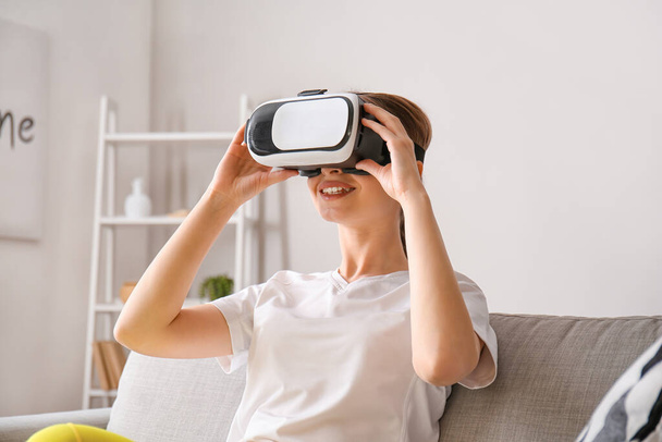 Young woman with virtual reality glasses at home - Foto, imagen