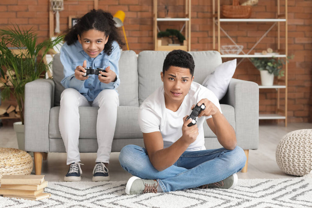 Afroamerykanin i siostra grają w grę wideo w domu - Zdjęcie, obraz