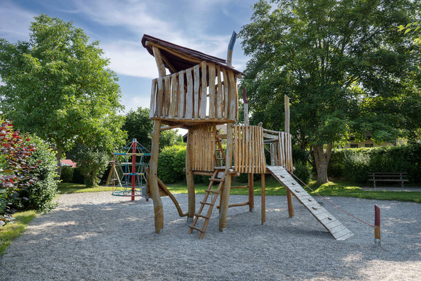 Casetta in legno su un parco giochi per bambini con ghiaia anticaduta in un piccolo parco ombreggiato con grandi alberi - Foto, immagini