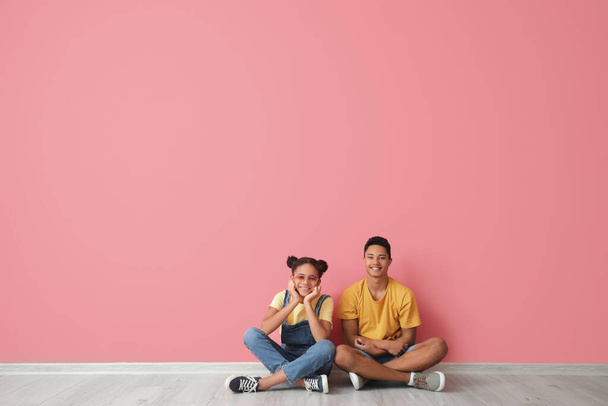 Fratello e sorella afroamericani seduti vicino al muro di colore - Foto, immagini