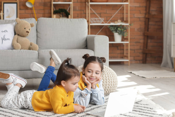 Cute little sisters with laptop watching cartoons at home - Foto, Bild