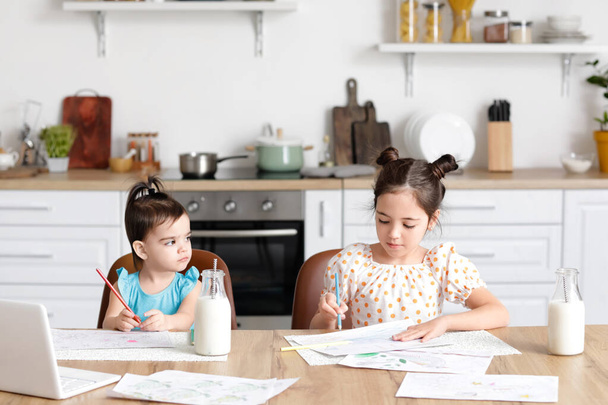 Cute little sisters drawing in kitchen - Photo, image