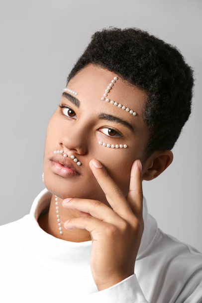 Retrato creativo del guapo chico afroamericano sobre fondo gris - Foto, Imagen