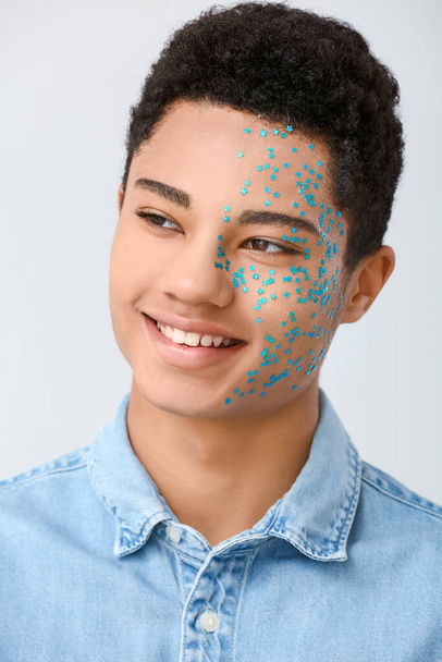 Retrato creativo del guapo chico afroamericano sobre fondo claro - Foto, Imagen