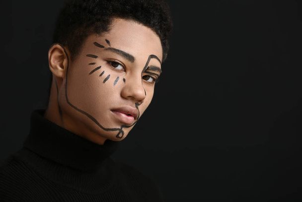 Junger Afroamerikaner mit Farbe im Gesicht vor dunklem Hintergrund - Foto, Bild