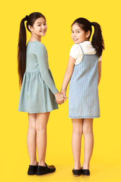 Cute Asian sisters on color background - Φωτογραφία, εικόνα