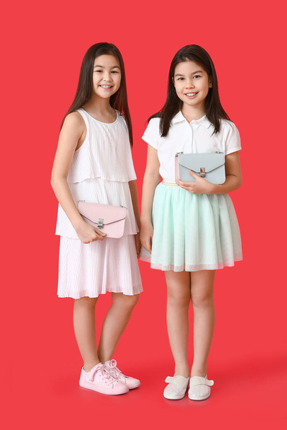 Cute Asian sisters with bags on color background - Photo, Image