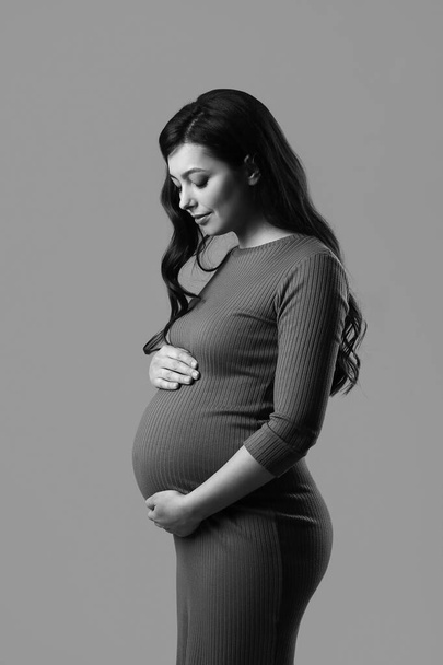 Красива вагітна жінка на сірому фоні
 - Фото, зображення