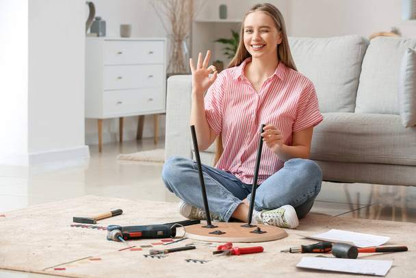 Jonge vrouw monteert meubels thuis - Foto, afbeelding