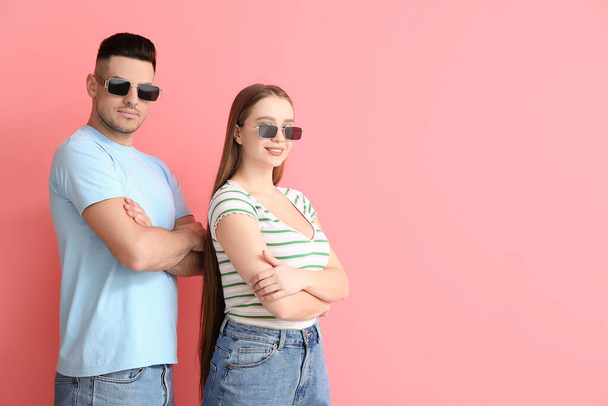 Молода пара в стильних сонцезахисних окулярах на кольоровому фоні
 - Фото, зображення