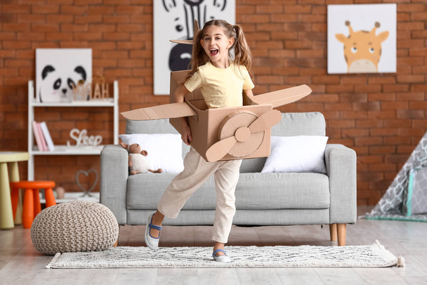 Kleines Mädchen spielt zu Hause mit Pappflugzeug - Foto, Bild