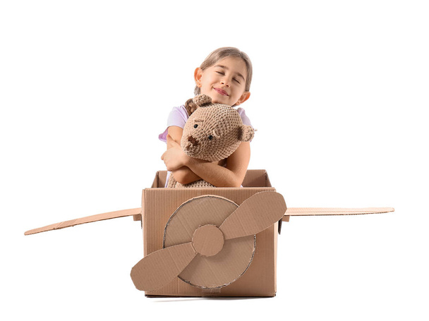 Little girl playing with toy and cardboard airplane on white background - Photo, image