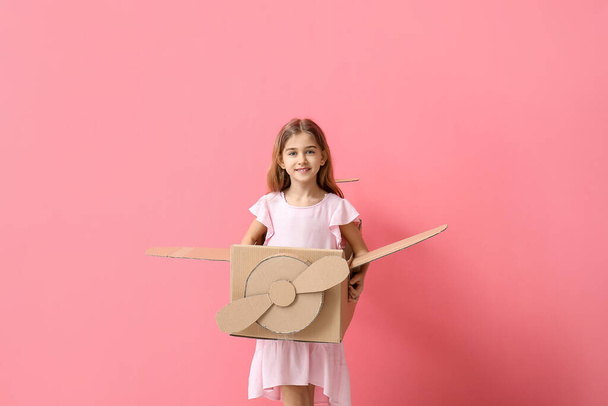 Little girl with cardboard airplane on color background - Photo, Image