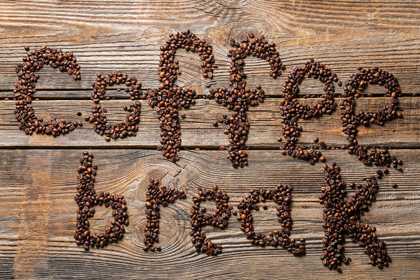 Tahta arka planda kahve çekirdeklerinden yapılmış kahve molası. - Fotoğraf, Görsel