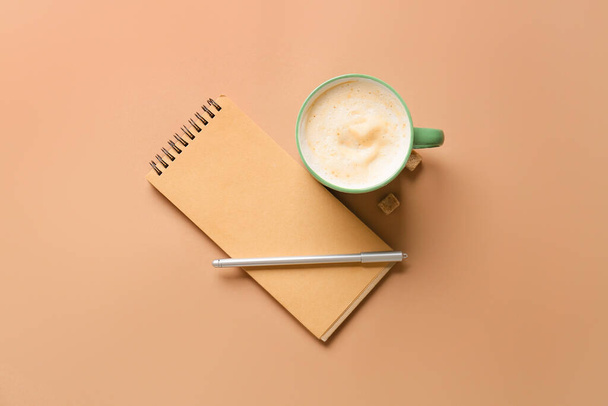 Cup of coffee with pen and notebook on color background - Foto, Imagem