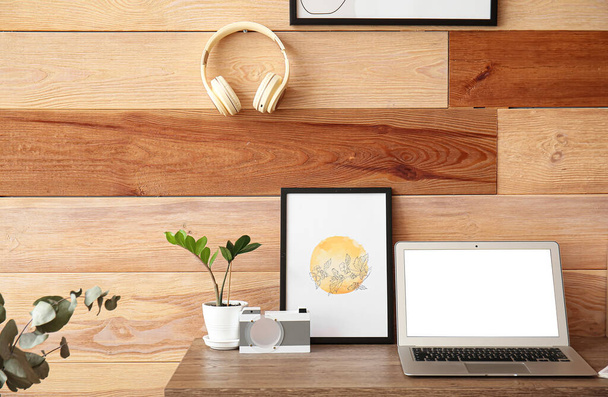 Modern workplace and headphones hanging on wooden wall - Photo, Image