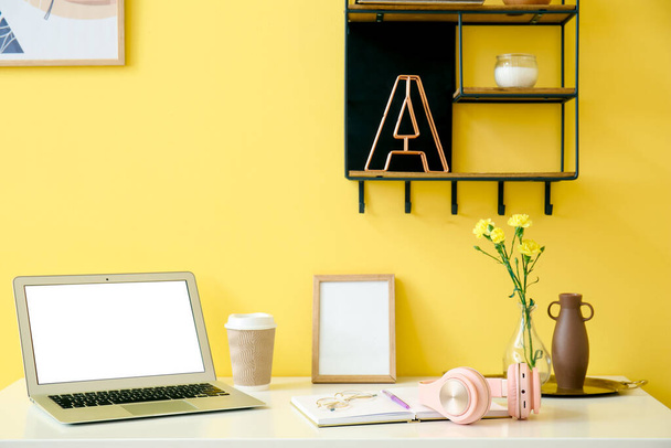 Σύγχρονη χώρο εργασίας με ακουστικά κοντά στον τοίχο χρώμα - Φωτογραφία, εικόνα